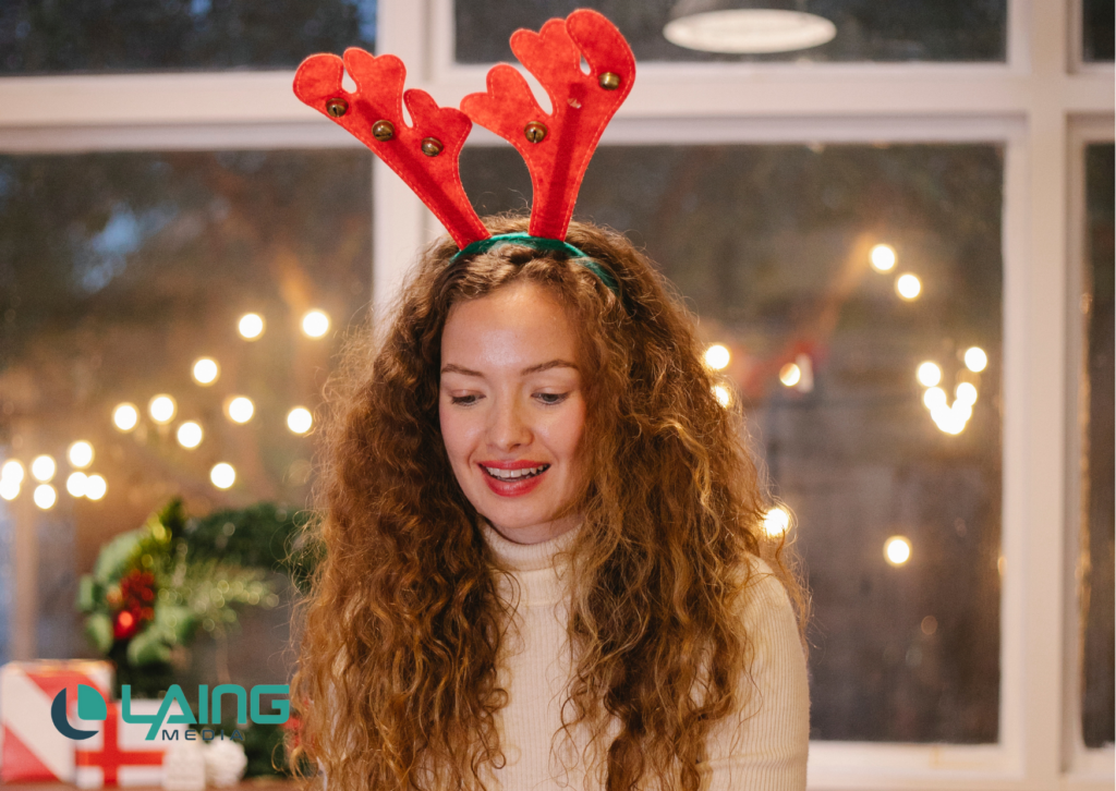Woman with long curly hair in Reindeer ears and holiday lights